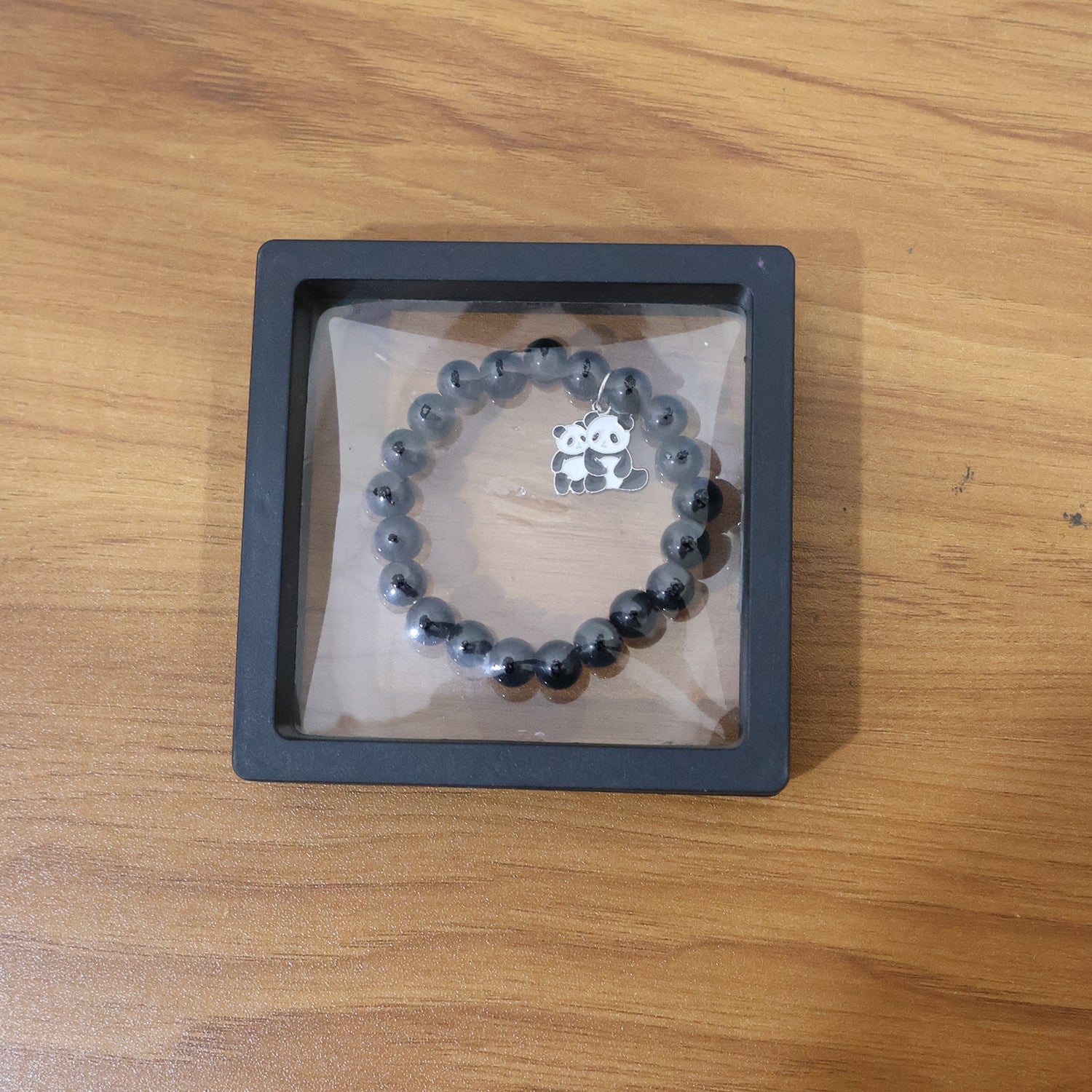 Lifestyle shot of black beaded stretch bracelet featuring cute panda charm on wrist.