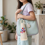 Glass water bottle showcasing cherry motif and flower charm, perfect for on-the-go