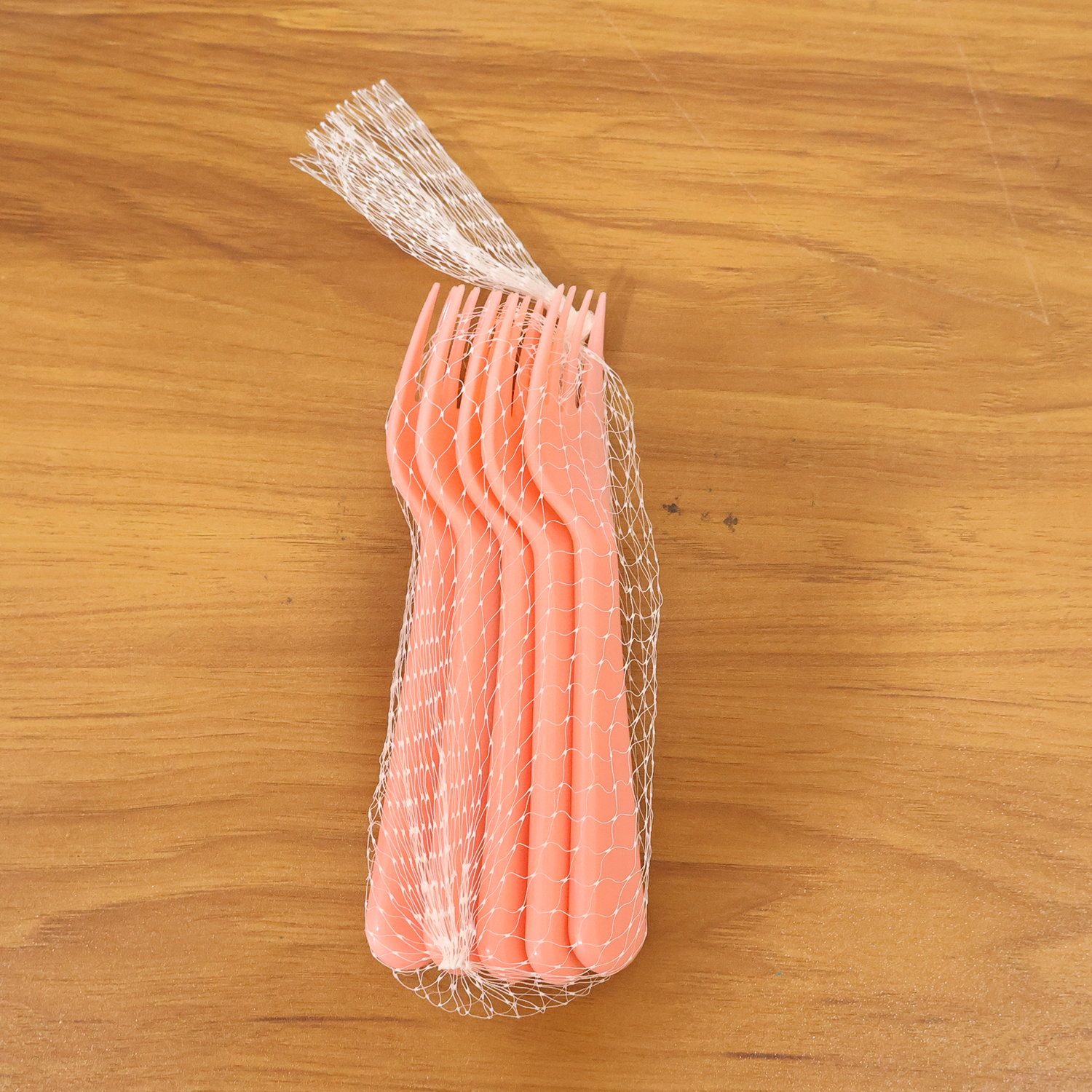 Pink plastic fork spoon being held, ready for use.