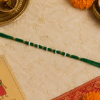 Cotton green thread rakhi featuring pearl and golden beads