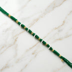 Traditional green rakhi showcasing pearl and golden bead accents