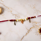 Close-up of Ganesh charm and feather on rakhi thread