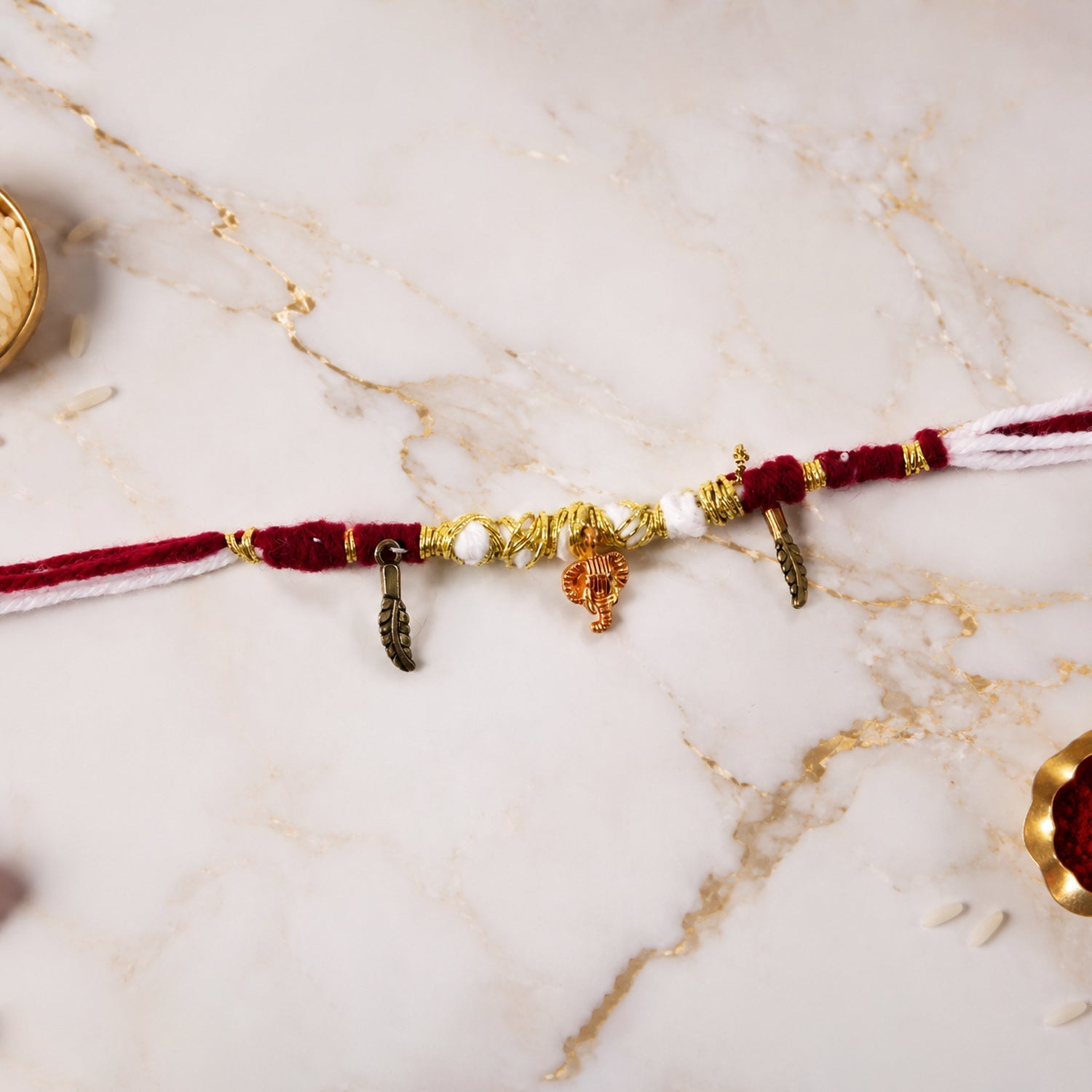 Close-up of Ganesh charm and feather on rakhi thread