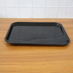 Black plastic serving tray used in home to serve tea cups and snacks