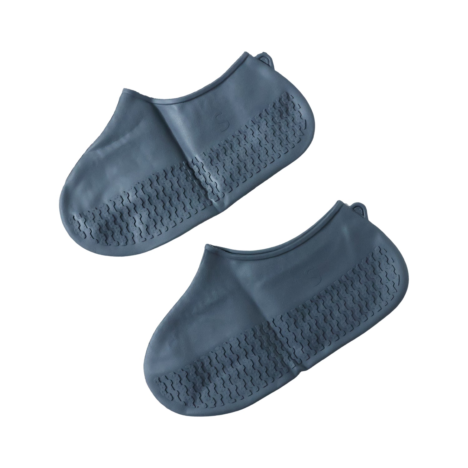 Silicone shoe cover with visible anti-skid sole pattern on a wet, tiled surface.