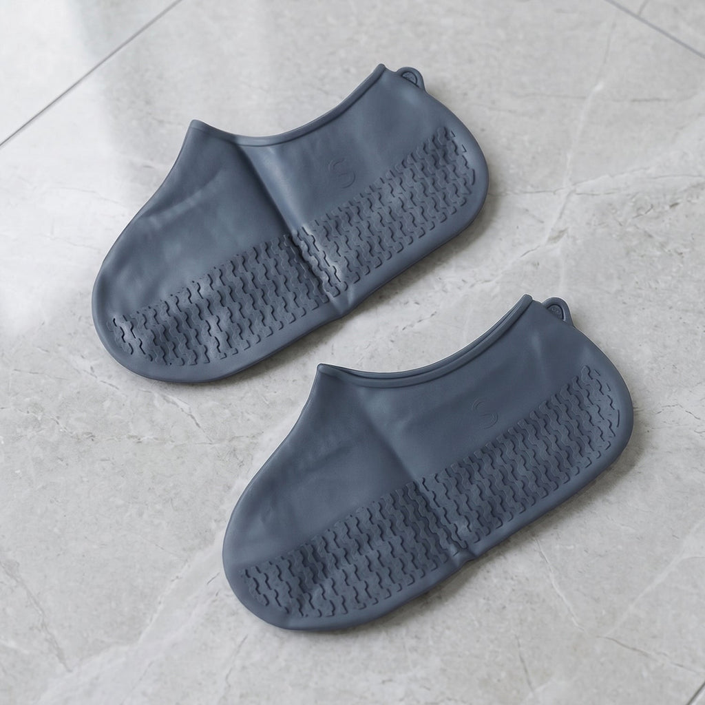 Person wearing silicone shoe covers outdoors on a wet pavement, walking through puddles.