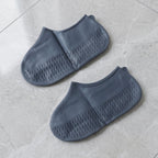 Person wearing silicone shoe covers outdoors on a wet pavement, walking through puddles.