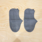 Waterproof silicone shoe covers being worn by a person walking through a muddy park.