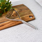 Potato masher placed in kitchen setting showing ergonomic handle