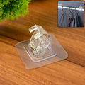 Transparent self-adhesive wall hook mounted on a smooth wall, supporting household items