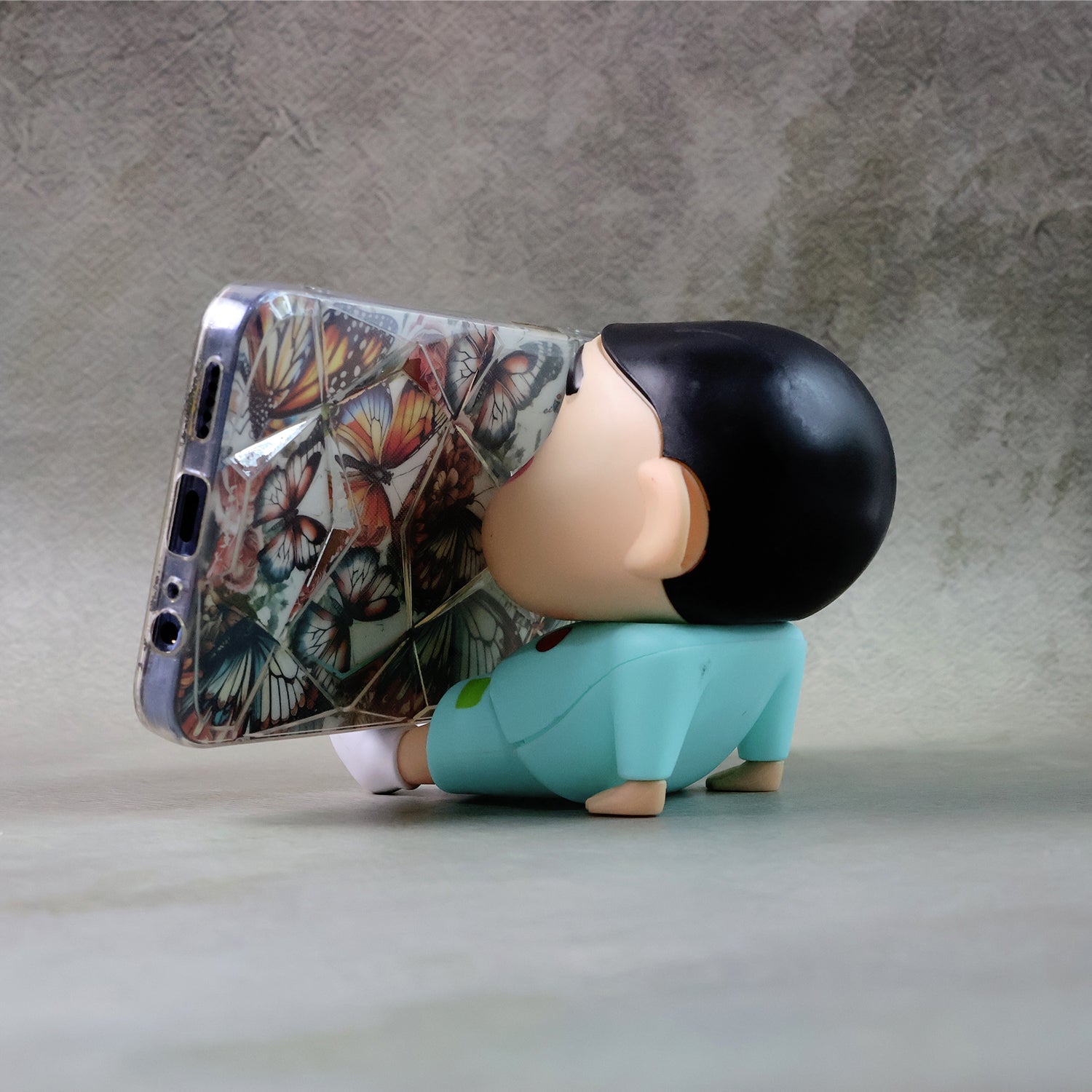 Mobile phone stand featuring a cartoon figurine design on desk