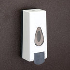 Close-up of the push-button mechanism on the wall mounted soap dispenser.