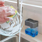 A grey 2-in-1 soap dispenser with a clean white sponge on a kitchen countertop.