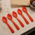 A person comfortably eating a meal from a plate using a white plastic spoon.