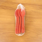 A stylish display of five white plastic spoons resting on a rustic wooden table.