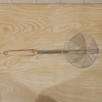 Cooking strainer utensil with long wooden handle for efficient frying
