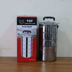 Stainless steel lunch box with different foods neatly separated in compartments.