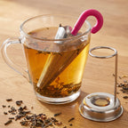 Umbrella tea strainer hooked on a ceramic teacup, brewing loose leaf tea for a perfect infusion.