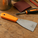 A BoltForce putty knife being used to smooth a surface during a home improvement project.