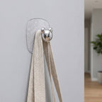 Clear plastic adhesive wall hooks organizing various household items neatly.