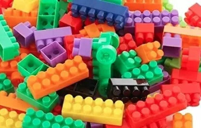 Hand holding a few small building blocks, demonstrating the compatible design.