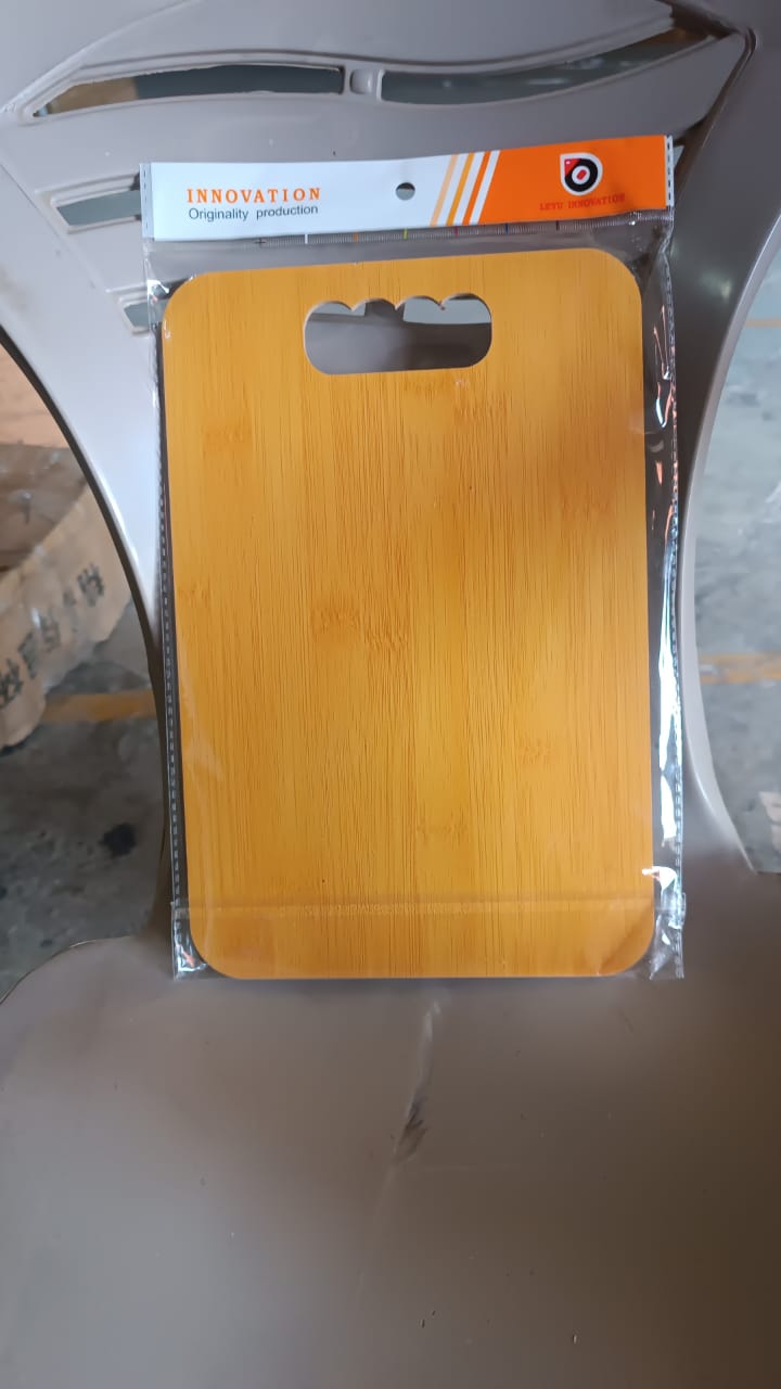Wooden chopping board hanging on hook by finger hole in neat kitchen setup