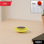 Hand holding yellow circular magnet securing paper on board