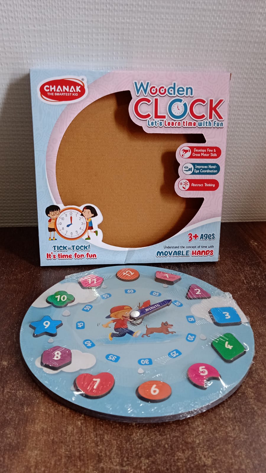Wooden educational learning clock toy displayed on table with colorful blocks