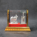 Silver-plated Kamdhenu cow idol set displayed in acrylic case with Tulsi plant
