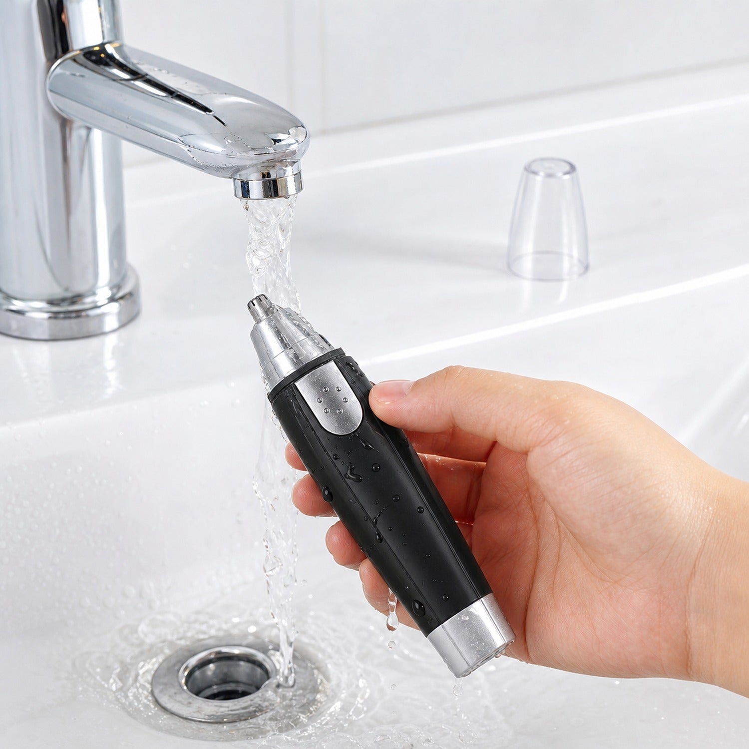 Ear and nose hair trimmer displayed next to AA batteries, showing its power source.