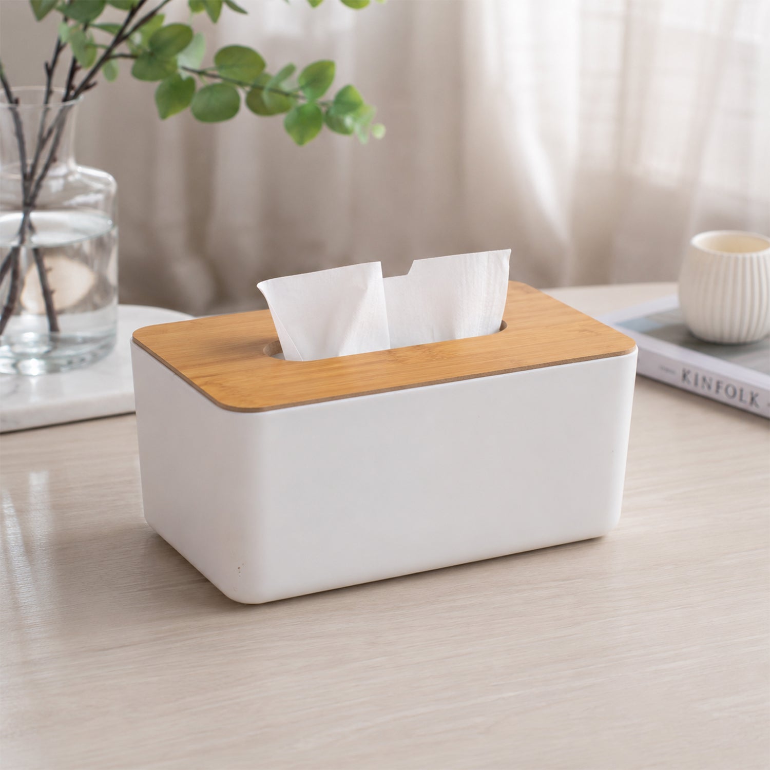 Eco-friendly bamboo tissue box holder on a bathroom counter with a green plant.