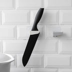 A sleek black punch-free wall hanging knife holder mounted on a kitchen wall, showcasing its modern design and space-saving functionality.