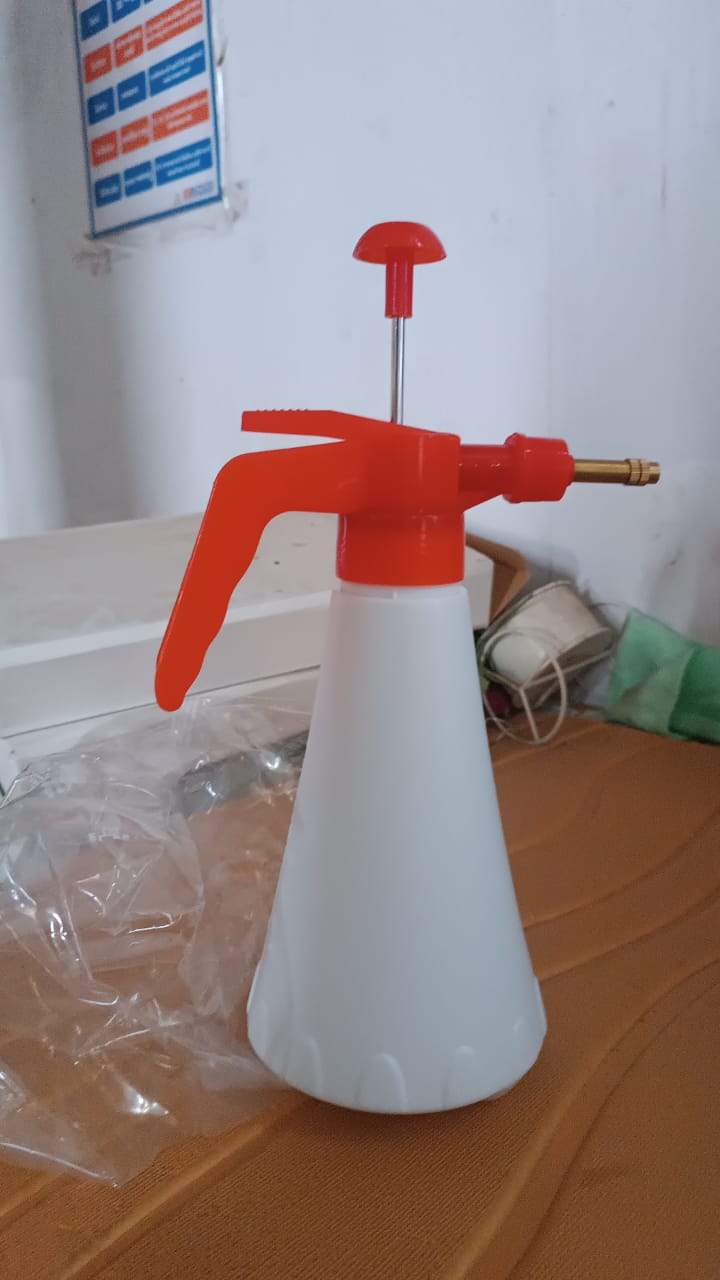 Person using handheld pressure water sprayer bottle for garden watering