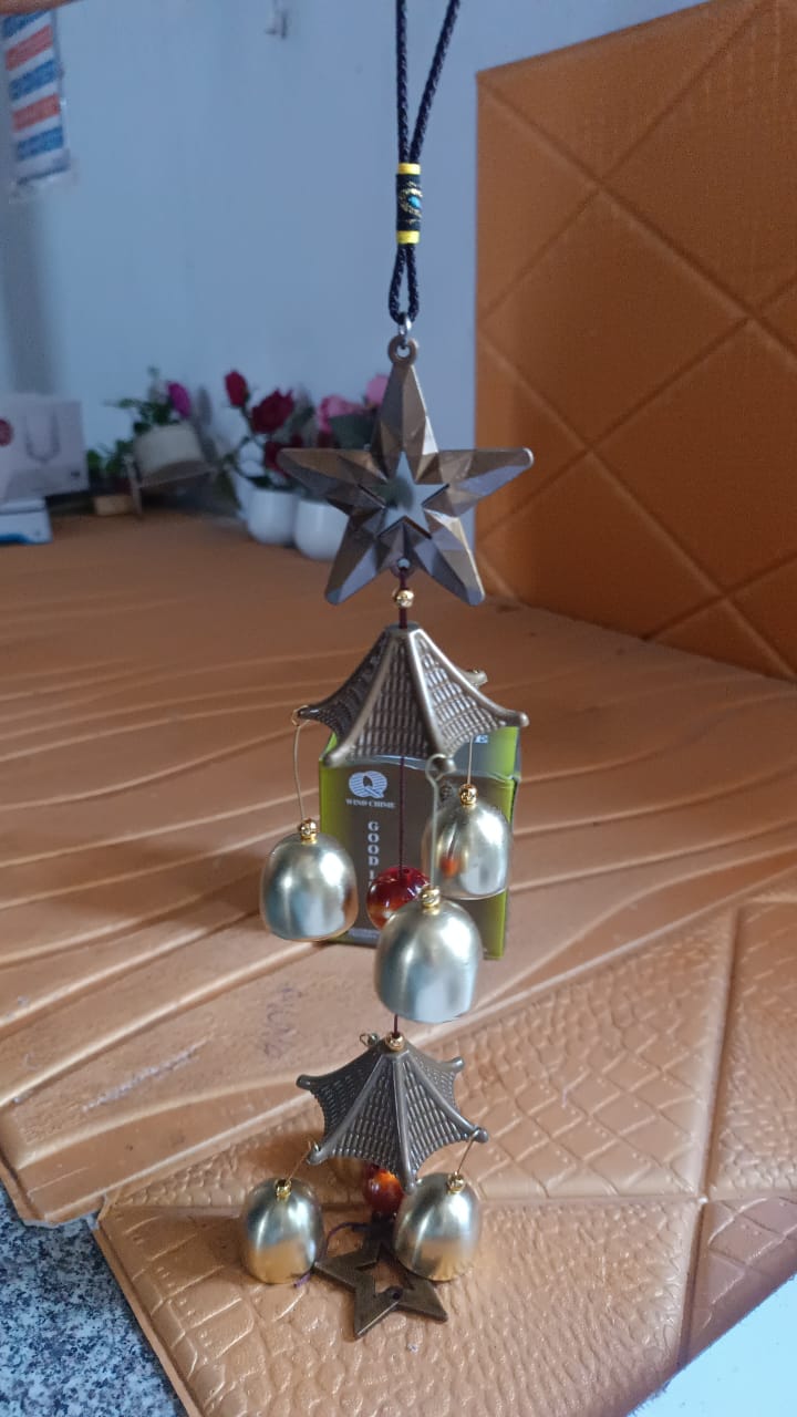 Decorative dragonfly wind chime hanging from porch beam, perfect for outdoor garden spaces