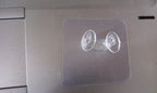 Minimalist transparent self-adhesive wall hook installed on a white wall.