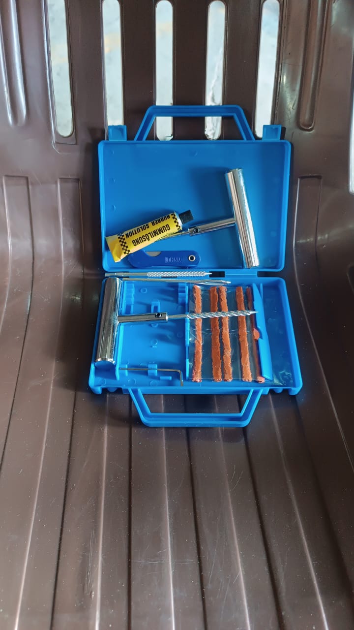 Mechanic demonstrating the portable tire repair kit being used to fix a motorcycle tire puncture.