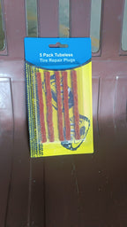 A hand holding a kit of brown tyre repair strips, demonstrating their compact size.