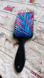 Packaging for the ergonomic hair brush alongside the product, ready for use.