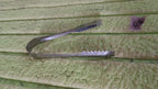 Stainless steel tongs resting on a rustic wooden surface, highlighting versatility.