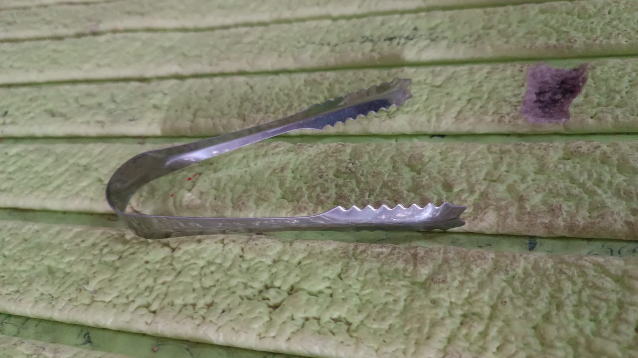 Stainless steel tongs resting on a rustic wooden surface, highlighting versatility.