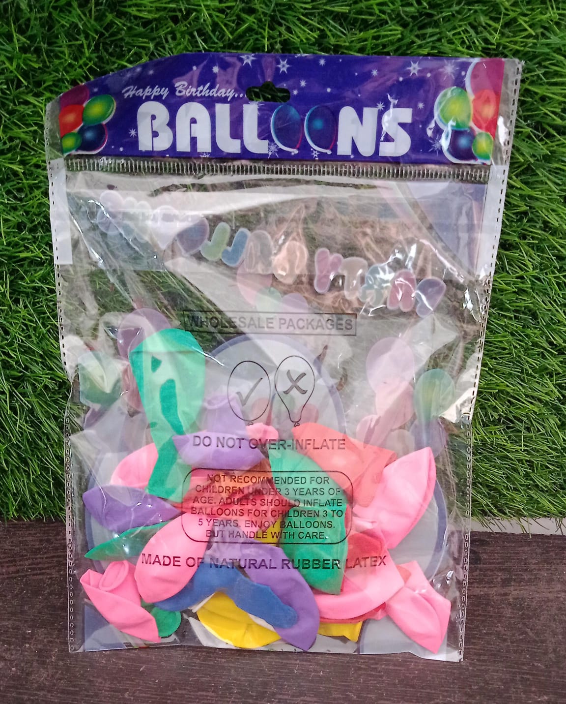 Hand holding vibrant multicolor latex balloons against a bright background.