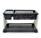 Black plastic dish drying rack with water collection tray on a kitchen counter.