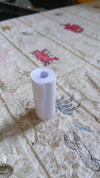 An overhead view of the thermal printer paper roll and a mini printer on a workspace.