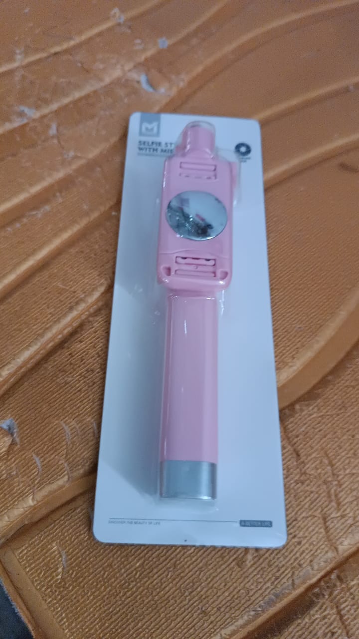 Pastel pink selfie stick with wired shutter button and rearview mirror visible