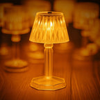 A close-up of the transparent crystal table lamp casting intricate light patterns.