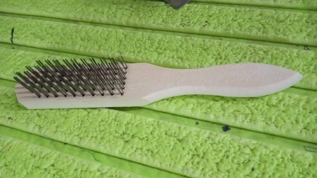 A close-up of the sturdy wooden handle and steel bristles connection.