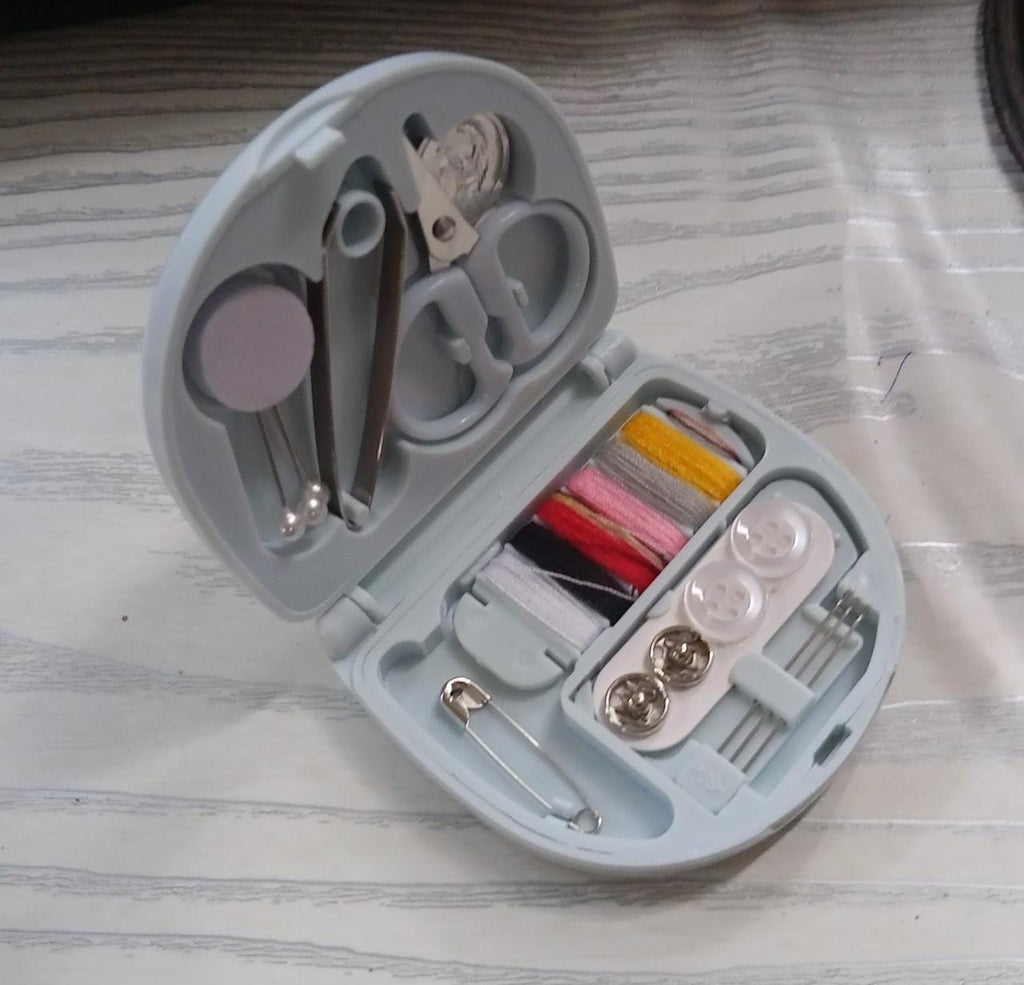 Close-up of small sewing tools like a needle threader, pins, and thimble from the kit.