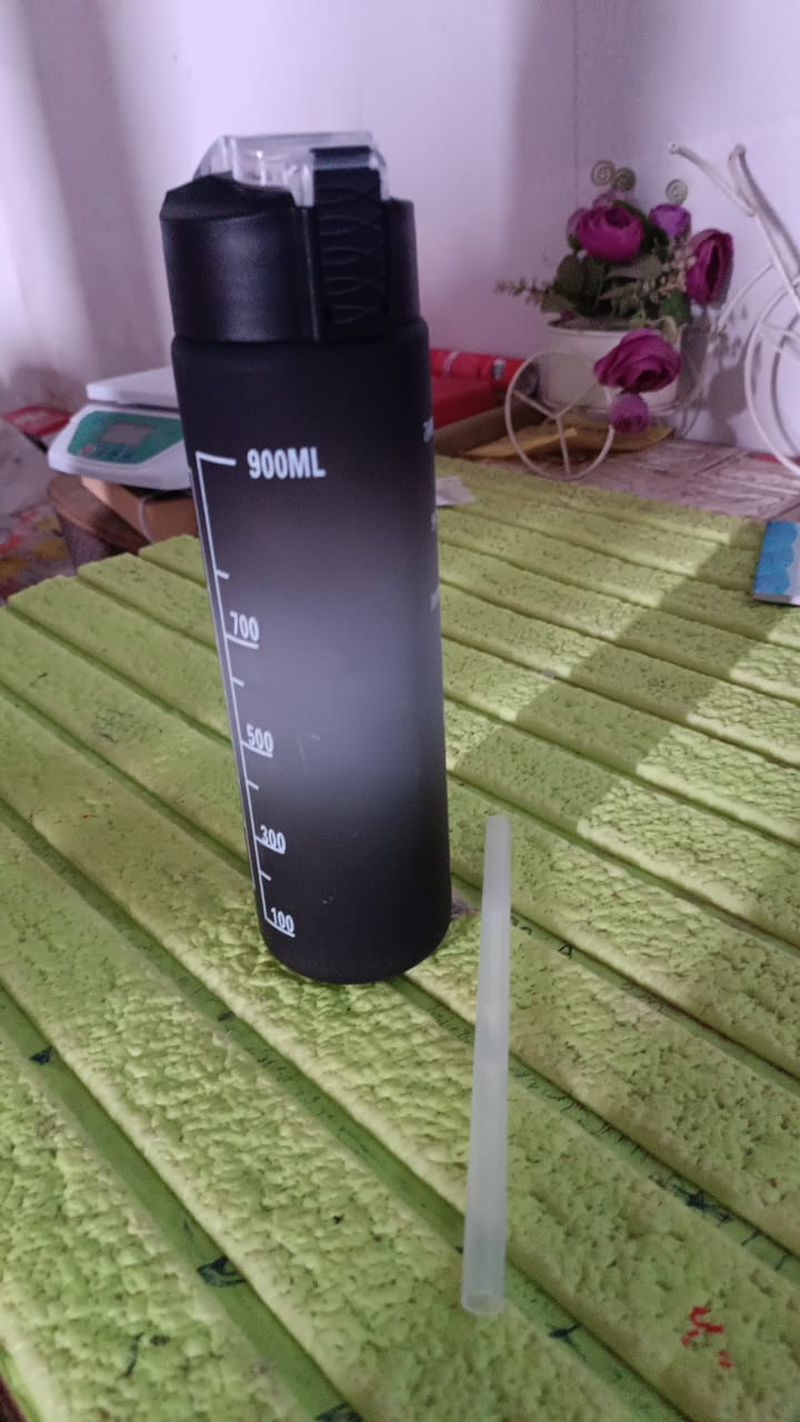 The black motivational water bottle placed on a clean background, emphasizing its design features.