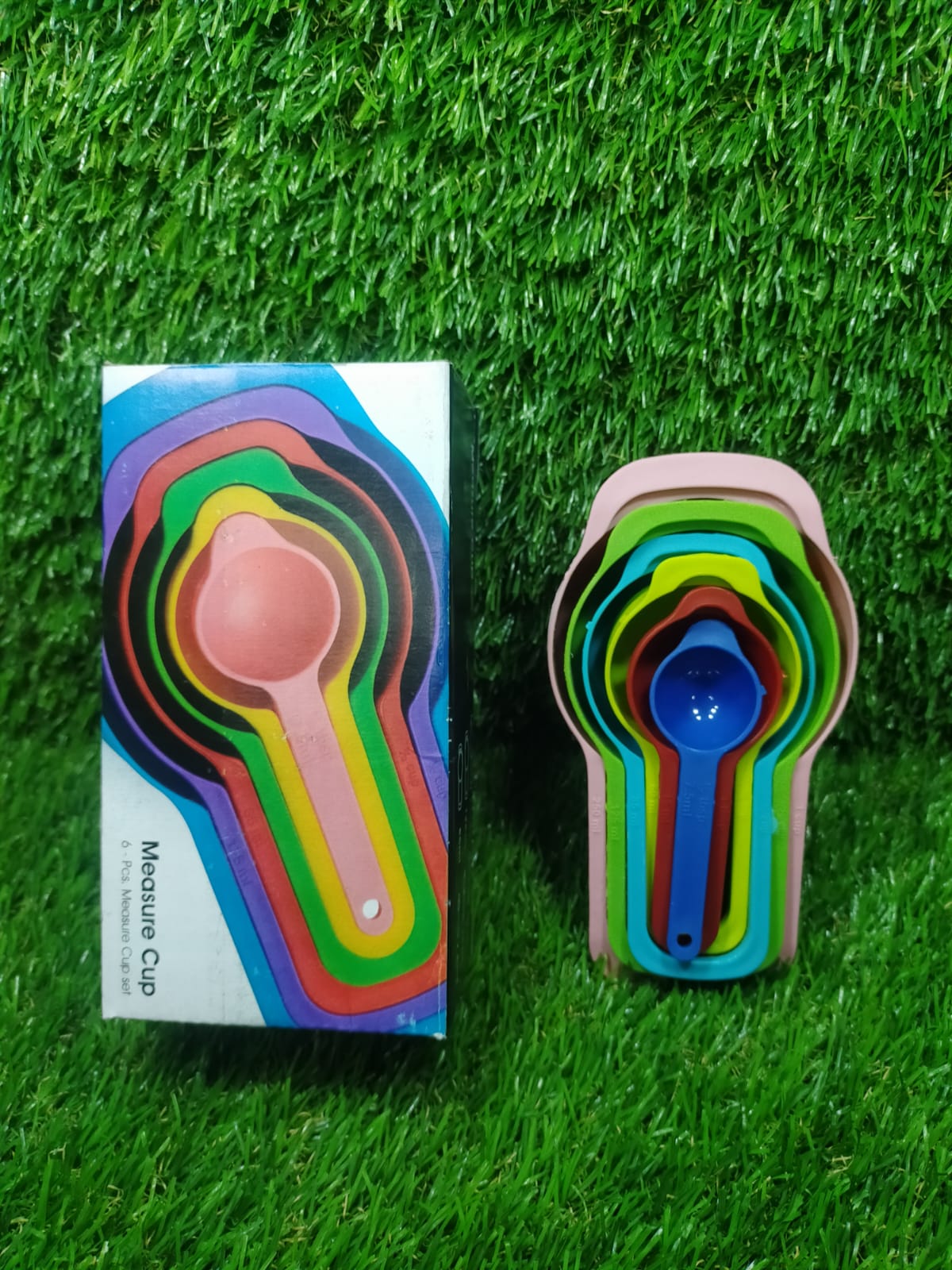 Detail shot of a pink plastic measuring spoon with easy-to-read measurement markings.