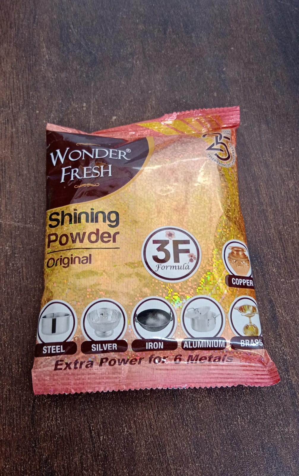 Person cleaning a metal pot with Wonder Fresh Metal Polishing Powder and a cloth.